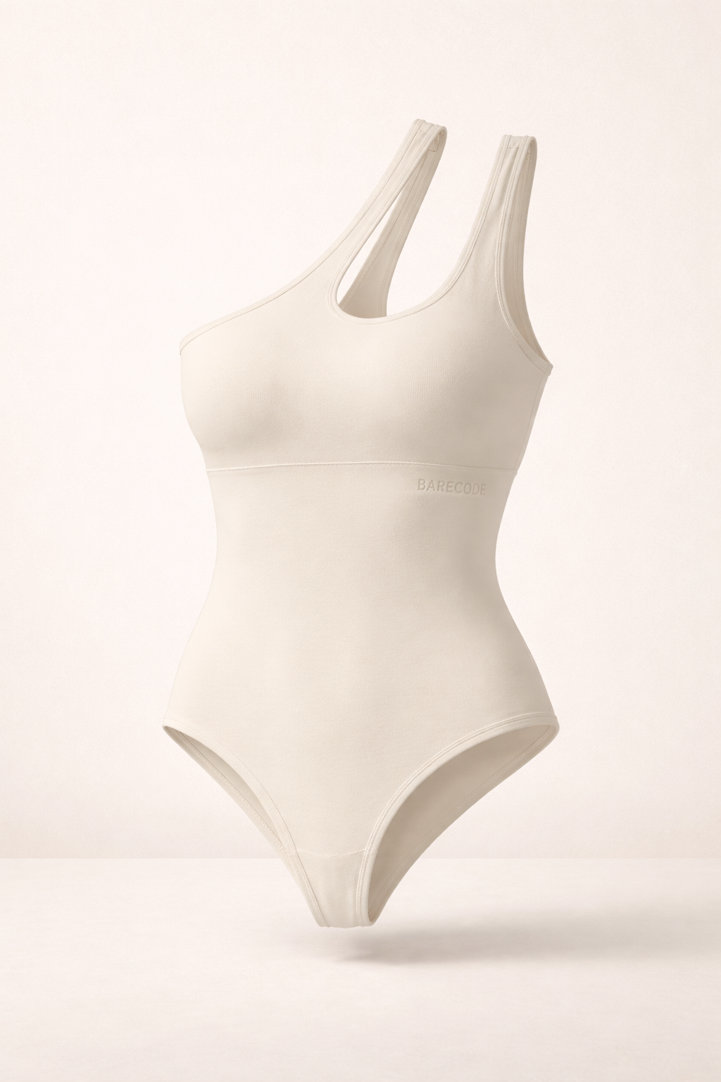 Asymmetrical one-shoulder sculpting bodysuit in bone, with side cutout.