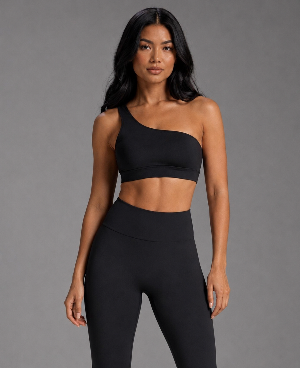 Black asymmetrical sports top with diagonal neckline and cropped hem, smooth knit