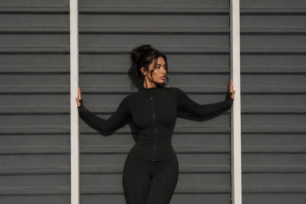 Black zip-up jacket with high neck, fitted long sleeves, front zipper