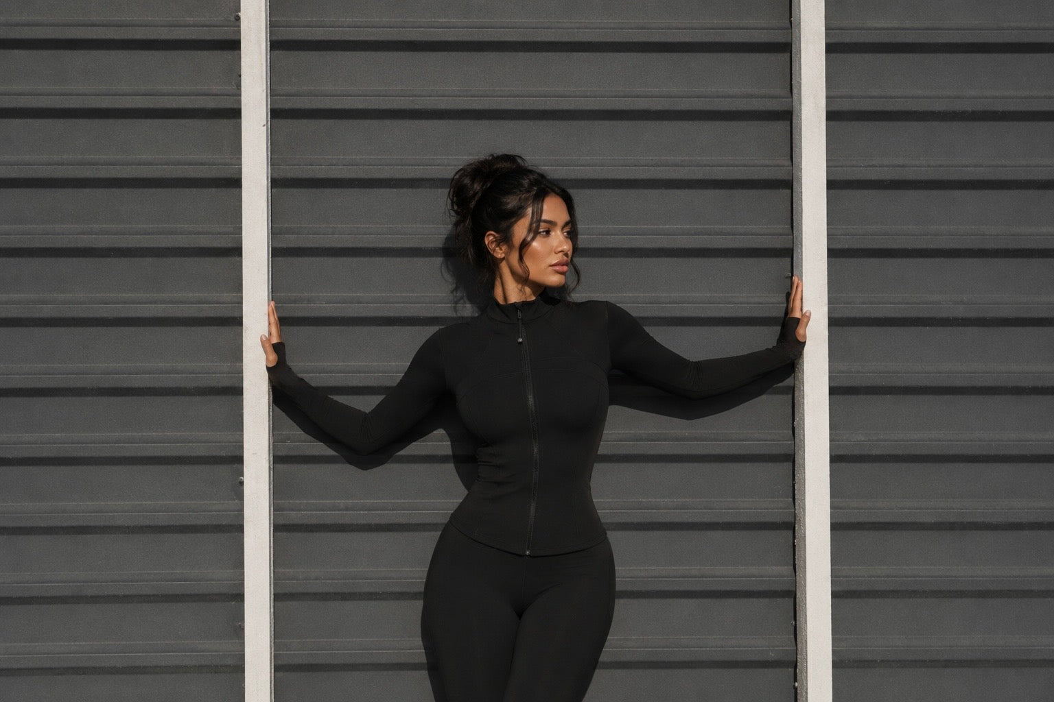 Black zip-up jacket with high neck, fitted long sleeves, front zipper